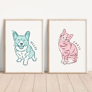 May include: Two framed illustrations of pets. The first illustration is of a light blue corgi with a white chest and a happy expression. The text "OLLIE" is written in a cursive font to the right of the corgi. The second illustration is of a pink cat with black stripes sitting with its head tilted to the side. The text "SADIE" is written in a cursive font to the right of the cat.