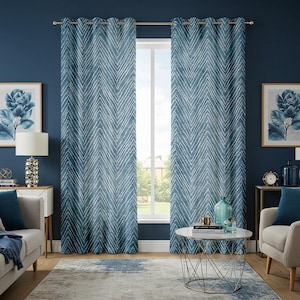 May include: Blue curtains with a white chevron pattern hang in front of a window. The room has blue walls, a gray rug, and framed floral art. A side table with a lamp and a coffee table with decor are in the room.