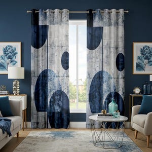 Op de afbeelding: Twee blauwe en witte gepatroneerde gordijnen met geometrische vormen hangen voor een raam. De gordijnen hebben een witte achtergrond met blauwe cirkels en abstracte vormen.