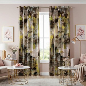 May include: A pair of brown and yellow patterned curtains with a watercolor abstract design. The curtains are hung on a window with a white frame and are made of a soft, textured fabric.
