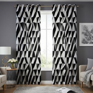 May include: A pair of black and white geometric patterned curtains with silver grommets hanging in a window. The curtains are fully drawn and the window is behind them.