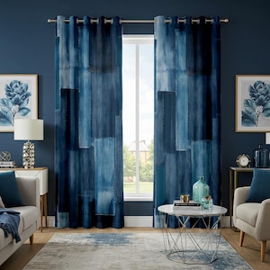 Op de afbeelding: Blauwe gordijnen in denimstijl met een patchwork-ontwerp. De gordijnen, in verschillende blauwtinten, hangen voor een raam. De kamer is ingericht met bijpassende blauwe accenten en kunstwerken. De gordijnen zijn ongeveer 200 cm lang.