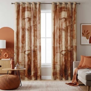 May include: Two brown and beige abstract patterned window curtains with metal eyelets. The curtains are hanging in front of a window. The room has a neutral colour palette with orange accents, including a pouffe, cushions, and artwork.