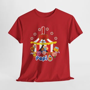 May include: Red t-shirt featuring a circus tent design with the number 1 and the word "Papi". The design includes cartoon characters and balloons, suitable for a child's first birthday celebration.