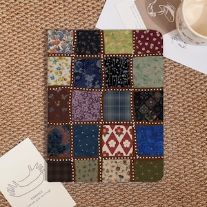 Könnte beinhalten: Ein Patchwork-Design mit quadratischen Stoffen mit Blumen- und anderen Mustern in Blau, Grün, Rot und Lila. Die Quadrate sind von einem braunen Rahmen und weißen gepunkteten Linien umgeben. Das Thema ist Vintage oder Cottagecore.