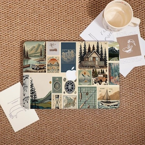 May include: A laptop skin featuring a collage of outdoor-themed illustrations in shades of blue, green, and beige. The design includes images of mountains, cabins, compasses, and a vintage car. The text "TODAY IS A GOOD DAY" is also visible.
