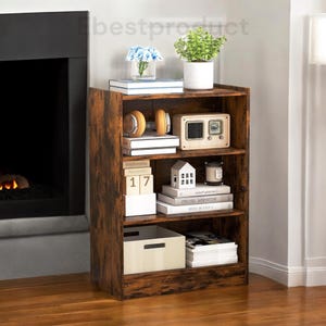 May include: A rustic brown wooden bookshelf with three shelves. The shelves are filled with books, a radio, a calendar, a candle, and other decorative items. The bookshelf is standing on a wooden floor.