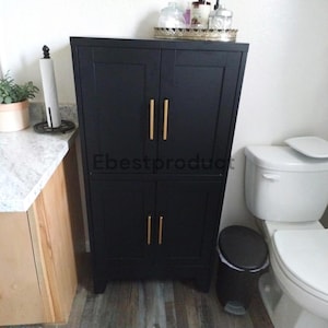 May include: A tall, matte black storage cabinet featuring four doors with vertical, brushed gold-tone metal handles. The cabinet has a clean, rectangular frame and is positioned in a room. The text Ebestproduct is visible on the front.