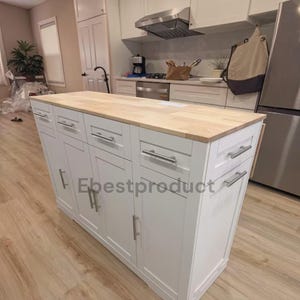 May include: A white kitchen island with a light wood countertop, featuring multiple drawers and cabinets with silver-toned horizontal handles. The unit has a rectangular shape and is positioned in a kitchen space. The text Ebestproduct is visible.