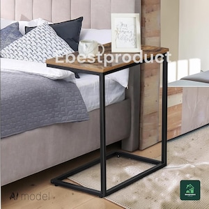 May include: A C-shaped side table with a rectangular brown wood-grain top and a black metal frame. The table holds a white ceramic mug and a white picture frame with the text You belong among the wildflowers printed in black script lettering.