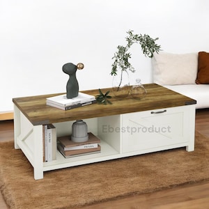 May include: A rectangular coffee table with a distressed wood top and white base. It features a drawer, an open shelf, and metal corner accents. Decorative items include books, vases, and a dark gray sculpture with a gold sphere.