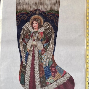 May include: A needlepoint canvas stocking featuring an angel with large wings, wearing a patchwork coat with fur trim, set against a dark blue background. A yellow measuring tape on the right shows a height of 33 inches. Text reads TT-AXS-403.