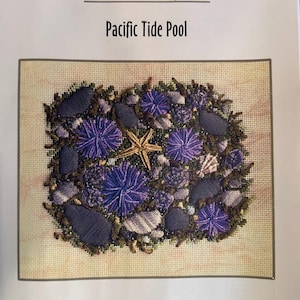May include: A needlepoint pattern titled Special Projects Pacific Tide Pool by Laura J. Perin Designs. The design features a central yellow starfish surrounded by purple sea urchins, grey stones, and green seaweed on a beige canvas background.