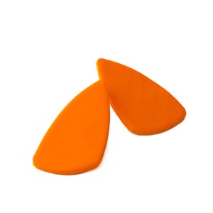 May include: Two bright orange, teardrop-shaped foam pieces with a smooth, matte texture. Each piece features a curved, asymmetrical silhouette with a pointed top and a wider, rounded base, presented against a plain white background.