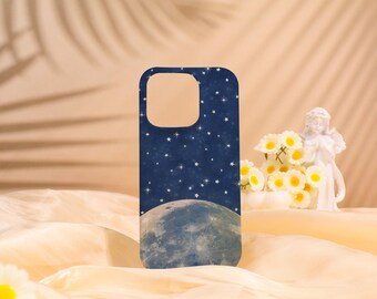 May include: A navy blue phone case featuring a celestial design. The case depicts a full moon at the bottom, a starry night sky, and a cutout for the camera. The case is displayed on a cream-colored fabric.