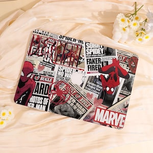 May include: A laptop case with a Spider-Man theme, displaying a collage of comic book panels and imagery. The design includes newspaper-style text, the Spider-Man logo, and illustrations of the superhero in red and black. The word "MARVEL" is also visible.