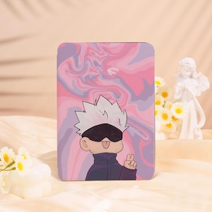 May include: A rectangular case featuring a cartoon character with white hair, a black blindfold, and a dark blue jacket. The background has a pink and purple marble design. The character is giving a peace sign.