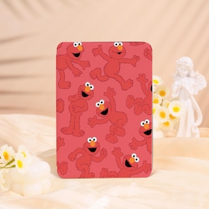 May include: A rectangular case featuring a repeating pattern of the Sesame Street character Elmo in various poses. The background is a solid red color. The case is likely for a phone or tablet.