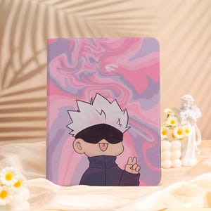 May include: A tablet case with a cartoon character with white spiky hair, a black blindfold, and a navy blue jacket. The background has a pink and purple marbled design. The character is giving a peace sign.