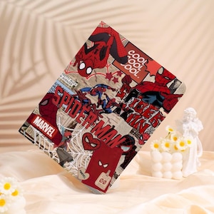 May include: A rectangular case featuring a collage of Spider-Man comic book art. The design includes images of Spider-Man in various poses, the word "SPIDER-MAN", and the Marvel logo. The color scheme is primarily red, black, and white.