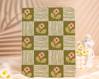 May include: A floral patterned notebook with a green and white checkered design. The notebook features pink flowers and green leaves. The background is a soft, neutral color.
