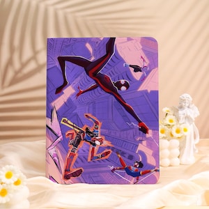May include: A purple tablet case featuring a dynamic illustration of Spider-Man in action. The artwork showcases Spider-Man in a red and black suit, set against a cityscape backdrop. The case is designed to protect a tablet.