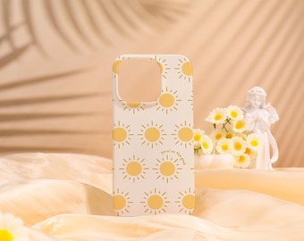 May include: White phone case with a repeating pattern of yellow suns and the phrase "focus on the good." The case has a cutout for the camera and buttons. The background is a soft, neutral color.