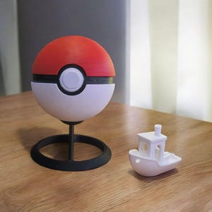 May include: A red and white Poke Ball with a black base, and a small white boat-shaped object.