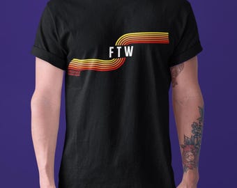 Puede incluir: Camiseta negra con un gráfico de estilo retro de un diseño de rayas amarillas, naranjas y rojas con el texto "FTW" en blanco.