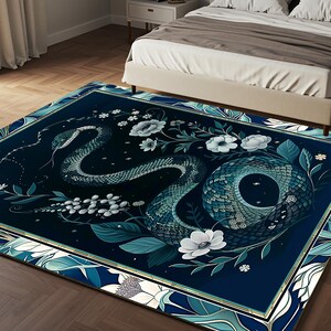 May include: A dark blue rug with a gold border features a stylized snake design with white flowers and leaves. The snake is curled up and has a textured, scaly appearance.