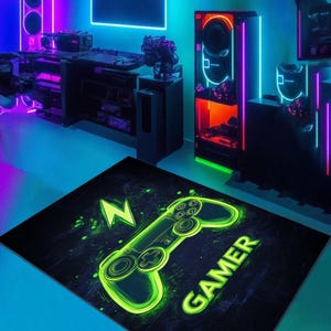 Puede incluir: Una alfombra de juego negra y verde con un mando de videojuego verde neón y la palabra "GAMER" en letras verdes neón.
