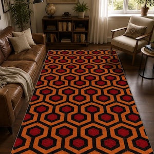 Könnte beinhalten: Ein rechteckiger Teppich mit einem sich wiederholenden geometrischen Muster aus ineinandergreifenden Sechsecken in den Farben Dunkelrot, leuchtendes Orange und Schwarz. Das Design besteht aus einer durchgehenden labyrinthartigen Struktur.