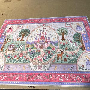 Peut inclure: Un panneau de tissu rectangulaire pr&eacute;sentant un ch&acirc;teau rose central entour&eacute; d'un jardin avec une licorne, un cerf, un lapin et un h&eacute;risson. La sc&egrave;ne comprend une cal&egrave;che, des arbres et quatre personnages en robe, encadr&eacute;s par une bordure florale rose.