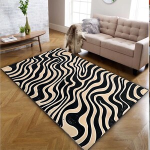 Könnte beinhalten: Ein schwarzer und cremefarbener Teppich mit einem wellenförmigen, abstrakten Zebrastreifenmuster. Der Teppich liegt auf einem Holzboden.