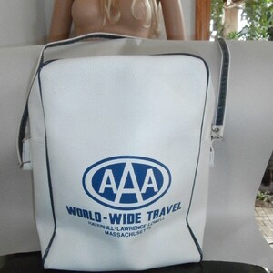 May include: White shoulder bag with a blue and white AAA World-Wide Travel logo. The bag has a rectangular shape with a shoulder strap and blue trim. The text "Haverhill-Lawrence-Lowell Massachusetts" is printed below the logo.