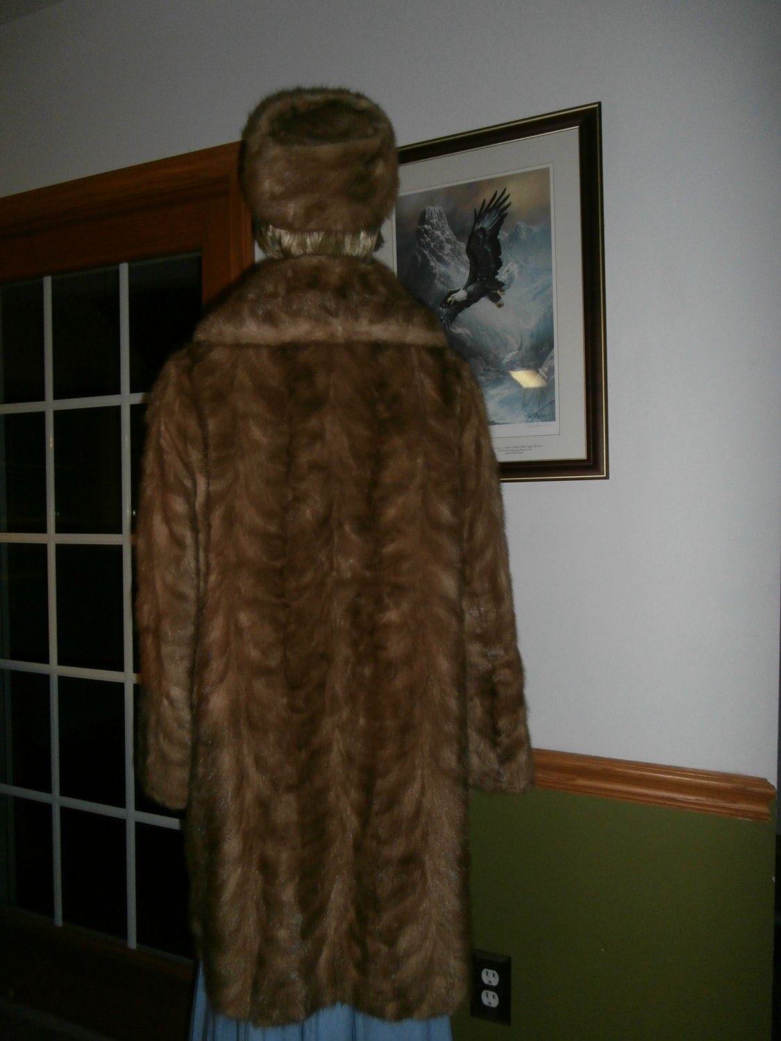 May include: A brown fur coat with a matching brown fur hat. The coat is long and has a collar. The hat is a cloche style.