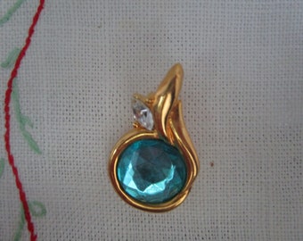 Peut inclure: Un pendentif en or avec une pierre précieuse bleue et un strass transparent. Le pendentif a la forme d'une larme.