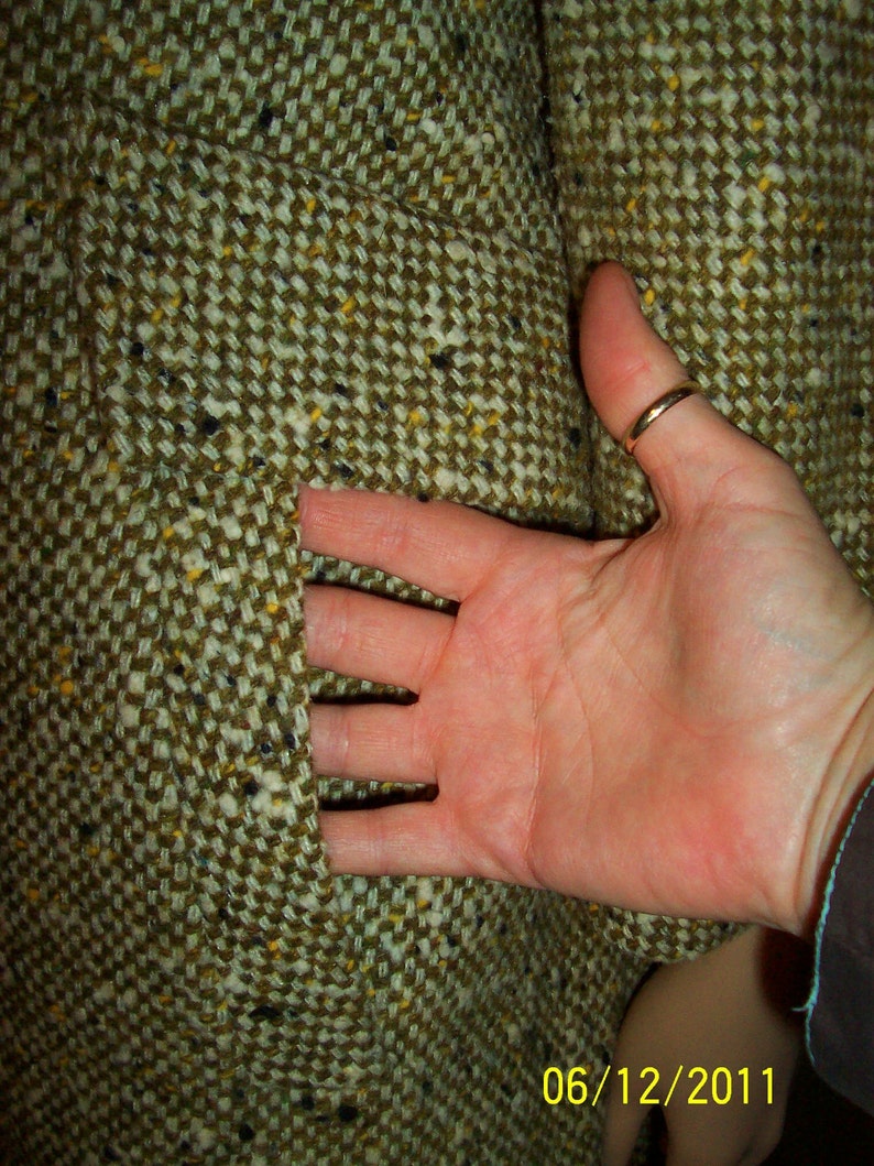 Puede incluir: Primer plano de una tela de tweed marr&oacute;n con un bolsillo. La tela tiene un sutil patr&oacute;n de motas amarillas y negras.