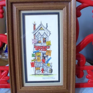 May include: A framed illustration of a multi-story building labeled Doctors Office, featuring various colorful signs including Storks Are Welcome, Exams, X-Rays, and Emergency. The artwork is signed Mason 1985 and enclosed in a brown wooden frame.