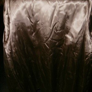 May include: A beige satin lining with a floral pattern. The lining is smooth and has a slight sheen.