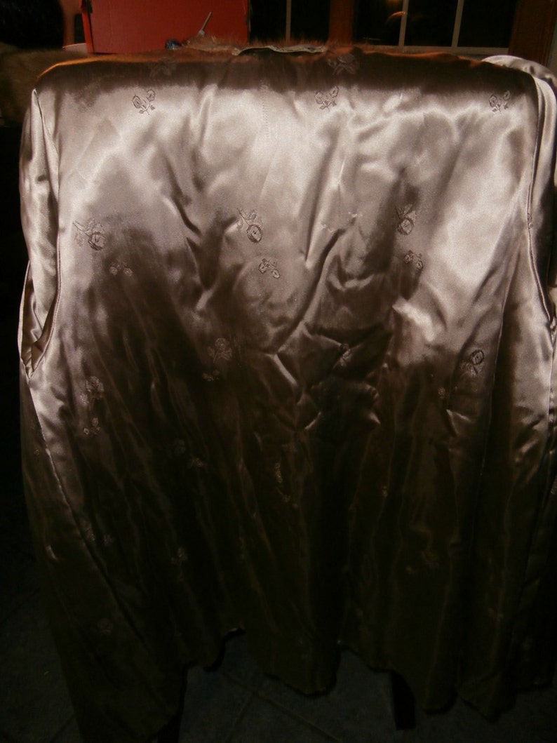 May include: A beige satin lining with a floral pattern. The lining is smooth and has a slight sheen.