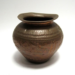 May include: A small, copper vase with an intricate, embossed design. The vase has a rounded body and a flared lip.