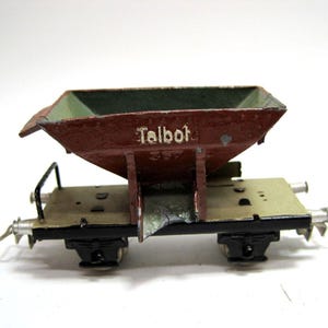 May include: A red and green toy train car with the word "Talbot" printed on the side. The car has a metal body and wheels.