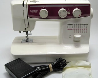 May include: White Brother XL-5130 sewing machine with a red and white control panel. The machine has a foot pedal and a white cord.