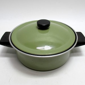 May include: A vintage green enamel pot with a matching lid and black handles. The pot has a silver rim and a black knob on the lid. This cookware is ideal for cooking and serving.