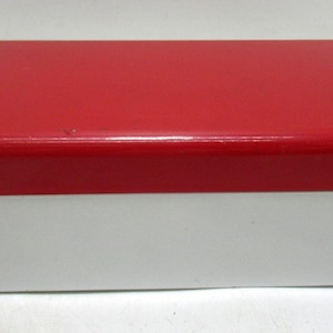 May include: A rectangular box with a glossy red lid and a white base. The box has rounded corners and a clean, minimalist design. The two-tone color scheme creates a striking visual contrast.