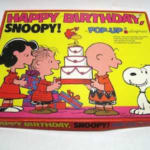 May include: A vintage "Happy Birthday, Snoopy!" pop-up party game box. The box features Snoopy, Charlie Brown, Lucy, and Linus, with a birthday cake and presents. The box is yellow, red, and white.