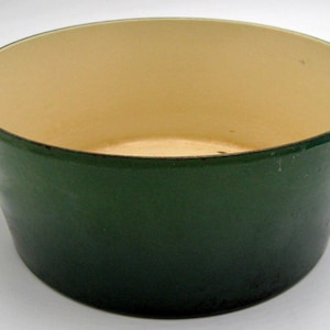 May include: A green enameled cast iron Dutch oven with two handles. The interior is white.