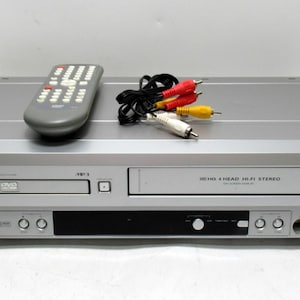 May include: Silver Sylvania DVD/VCR combo unit with a remote control and AV cables. The unit has a DVD tray, a VCR slot, and various control buttons. The remote is gray with numerous buttons. AV cables have red, yellow, and white connectors.