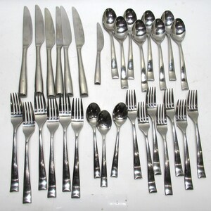 May include: A collection of stainless steel flatware, including forks, knives, and spoons. The silverware has a simple, modern design with a polished finish. The set includes multiple place settings, ideal for a large gathering or family meals.